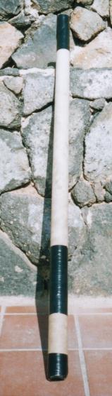 De zelfgemaakte vakantie-didgeridoo van een kartonnen koker en isolatietape, rechtop tegen een stenen muur