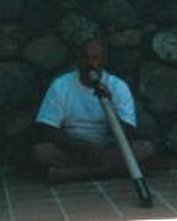 Zittend op de grond wordt de vakantie-didgeridoo bespeeld, met de opening op de tegels
